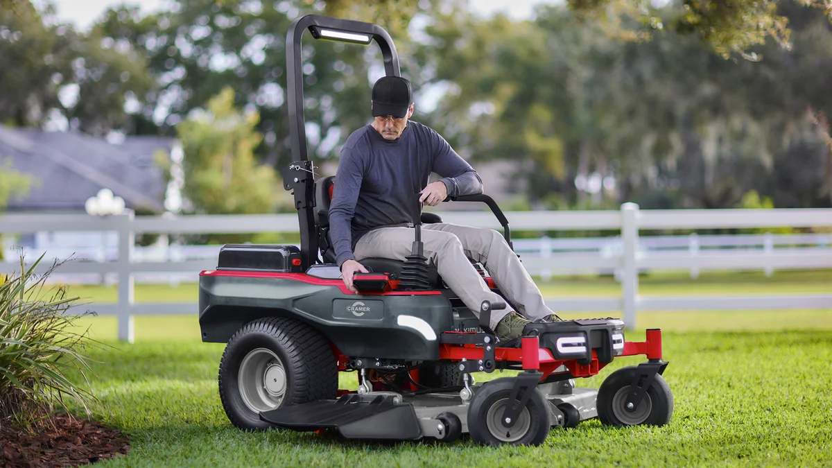 Tondeuse autoportée Zero-Turn Cramer Maximus 82ZT122 rouge et noire sur une grande pelouse verdoyante